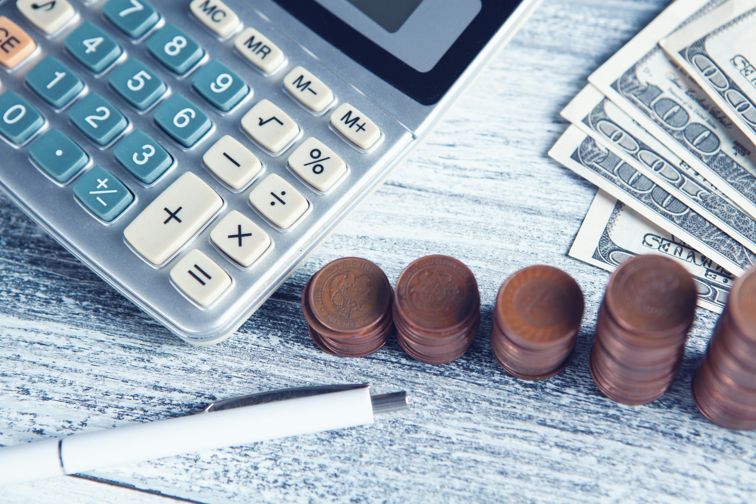 Calculadora, caneta e dinheiro sobre mesa representando o risco financeiro de erros comuns na compra de RIs e Savings Plans